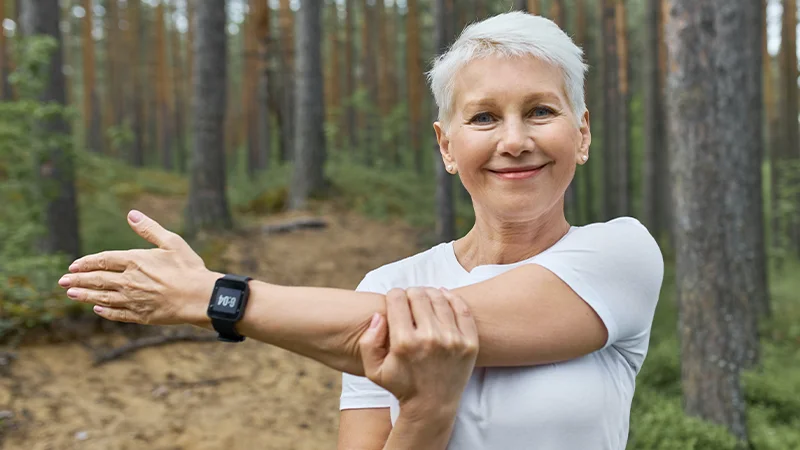 portrait short haired retired female wearing whit t shirt smart watch her wrist track progress running