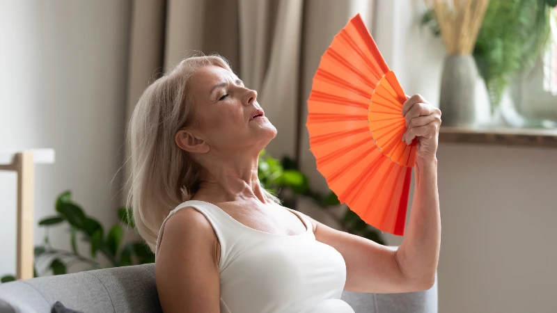 Žena se hladi lepezom zbog valunga u menopauzi