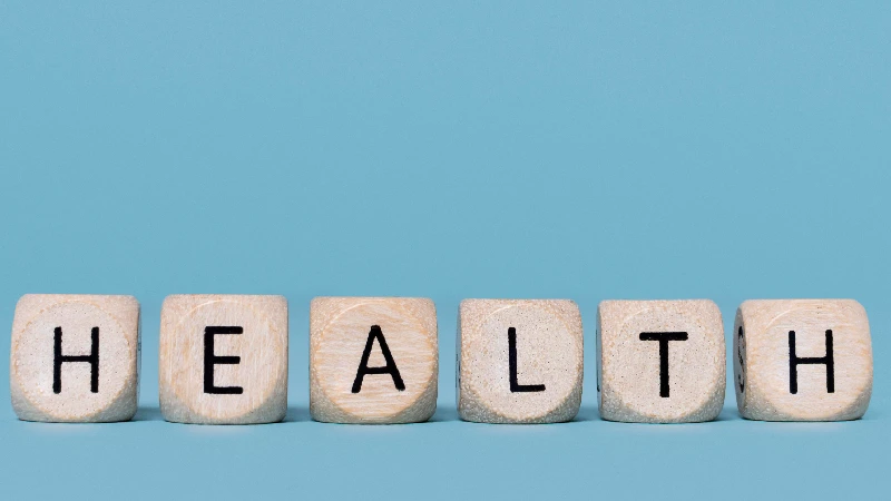 Drvene kockice sa slovima koje formiraju reč “HEALTH” na plavoj pozadini, koncept zdrav način života
