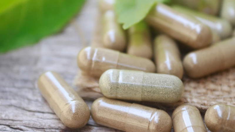 Moringa kapsule sa prirodnim ekstraktom na drvenoj podlozi sa zelenim listom