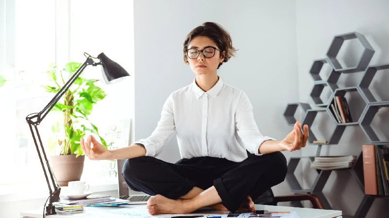 Žena meditira na radnom mestu kako bi smanjila stres i umor