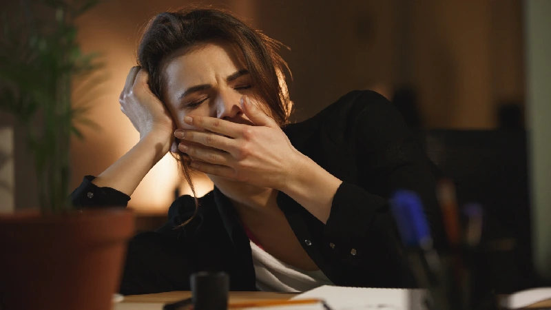 Umorna žena zeva za radnim stolom – umor i stres na poslu